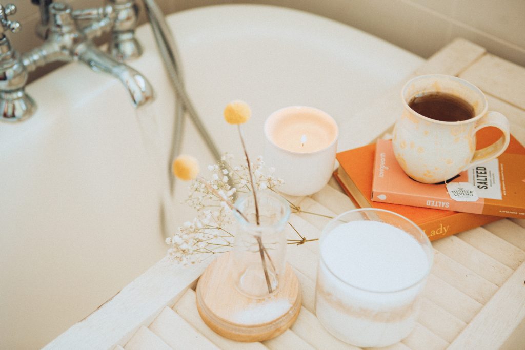 Image of a self care Sunday bath with bubbles, a candle, a cup of coffee and relax. 